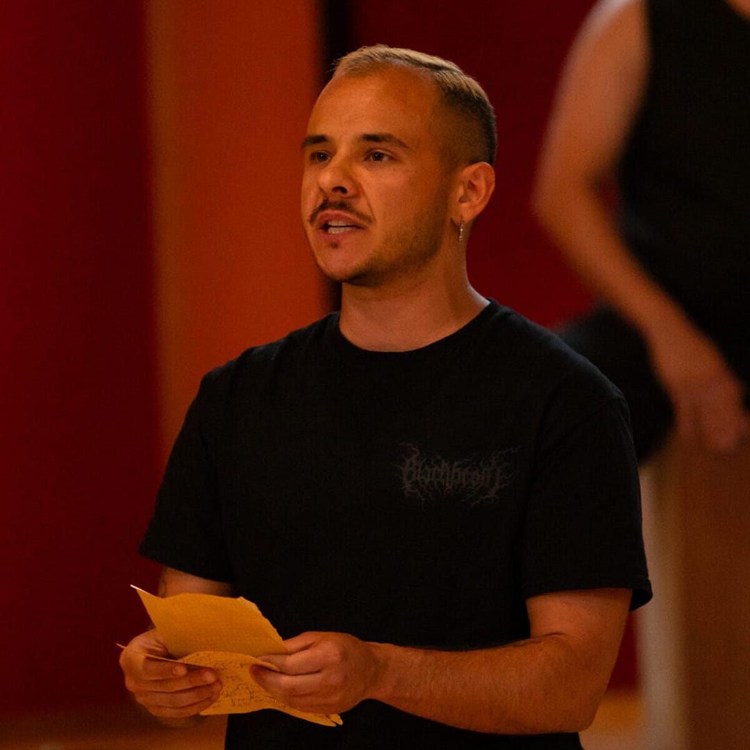 Holden Madagame in a black shirt with a piece of paper in their hands.